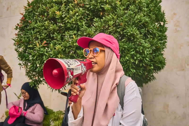 Ainun spreekt zich uit via een megafoon tijdens een demonstratie.